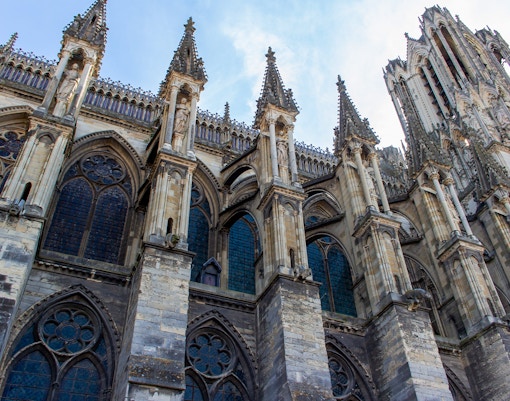 Notre-Dame de Reims, France, showcasing Gothic flying buttresses and detailed stone carvings.