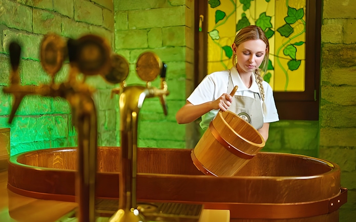 Spa Beerland staff preparing a wooden beer bath with taps in the background.