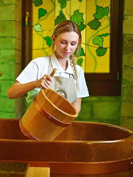 Spa Beerland staff preparing a wooden beer bath with taps in the background.