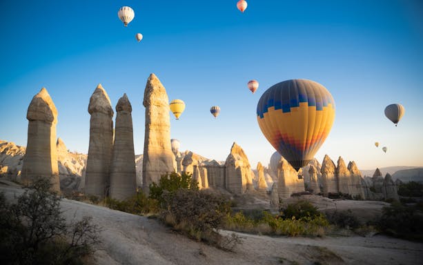 Hot air balloons over rock formations in Love Valley, Cappadocia, Turkey.