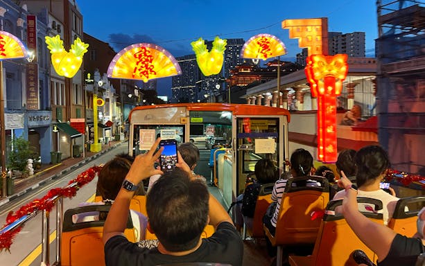 People enjoying a Chinatown Light Up Tour on a bus, capturing vibrant street decorations.