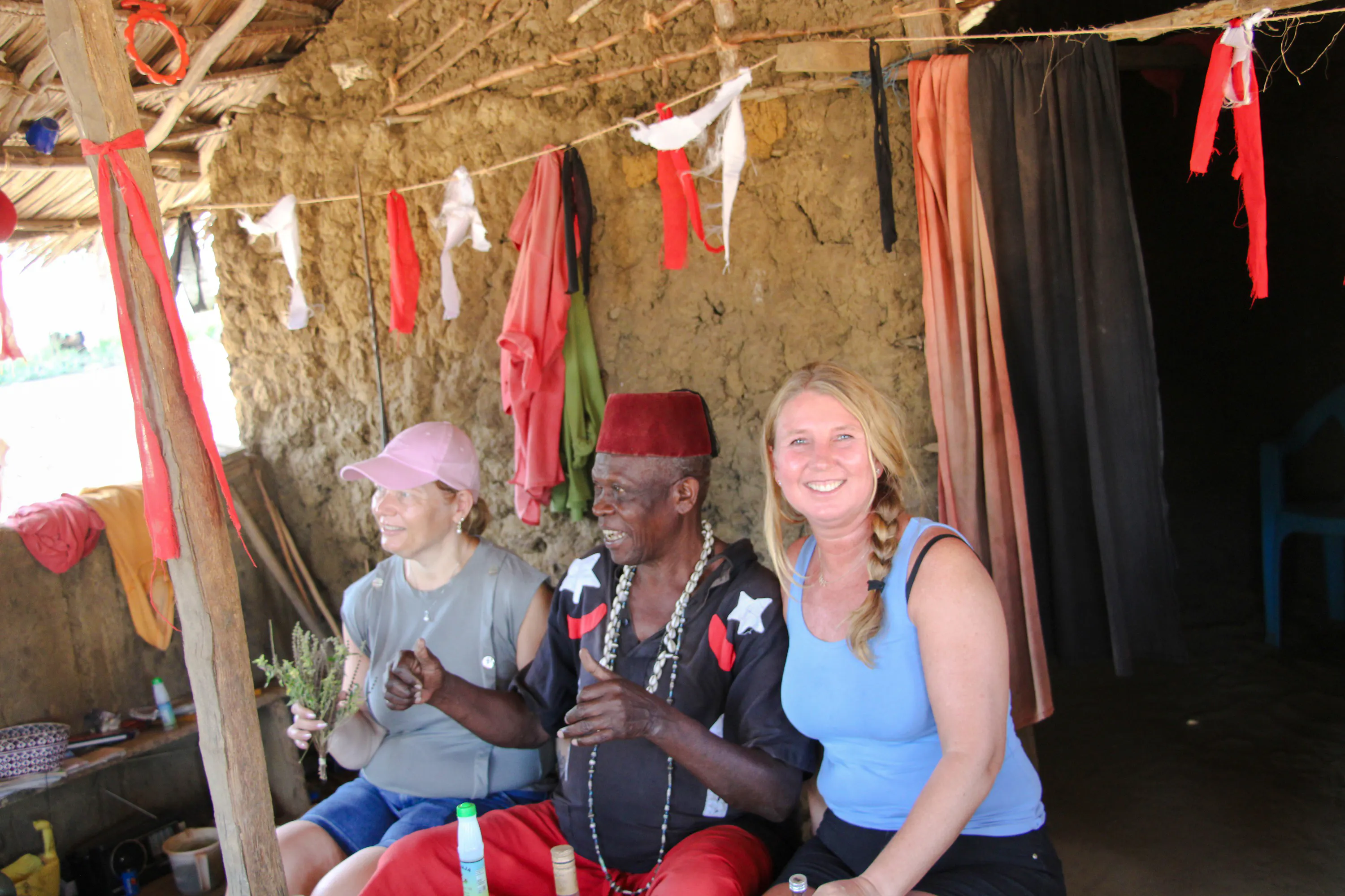 Giriama elder with tourists in a traditional hut during cultural dance show, Diani Beach.
