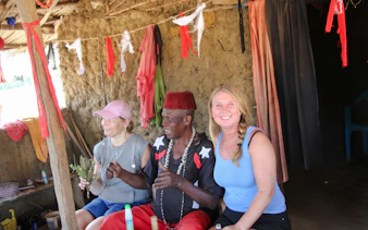 Giriama elder with tourists in a traditional hut during cultural dance show, Diani Beach.