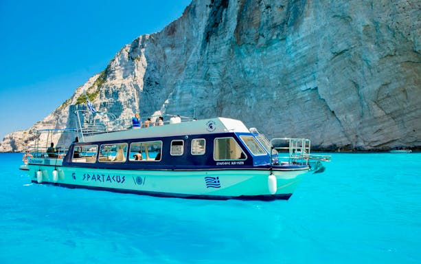 Glass bottom boat near cliffs at Shipwreck Beach, Zakynthos, during Blue Caves Land & Sea Tour.