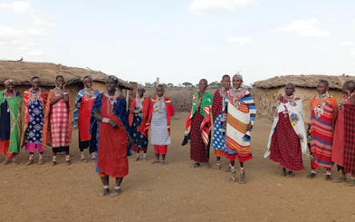 Maasai women in traditional attire outside huts in Amboseli, Kenya.