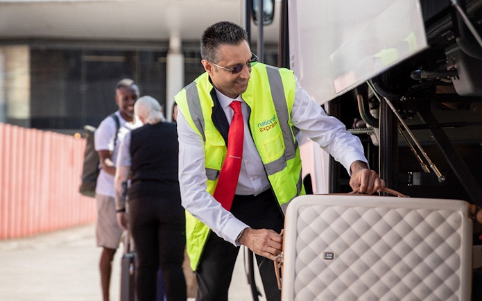 Bus staff loading luggage for Stansted Airport to London Victoria route.