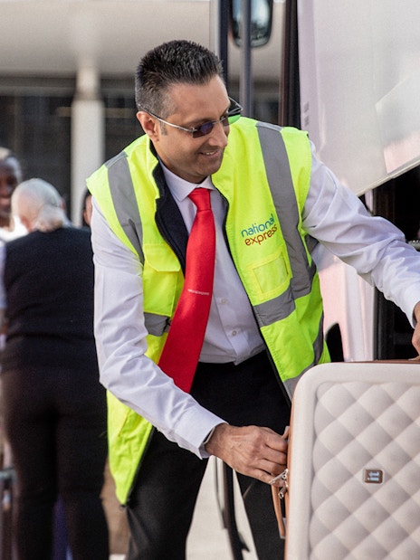Bus staff loading luggage for Stansted Airport to London Victoria route.