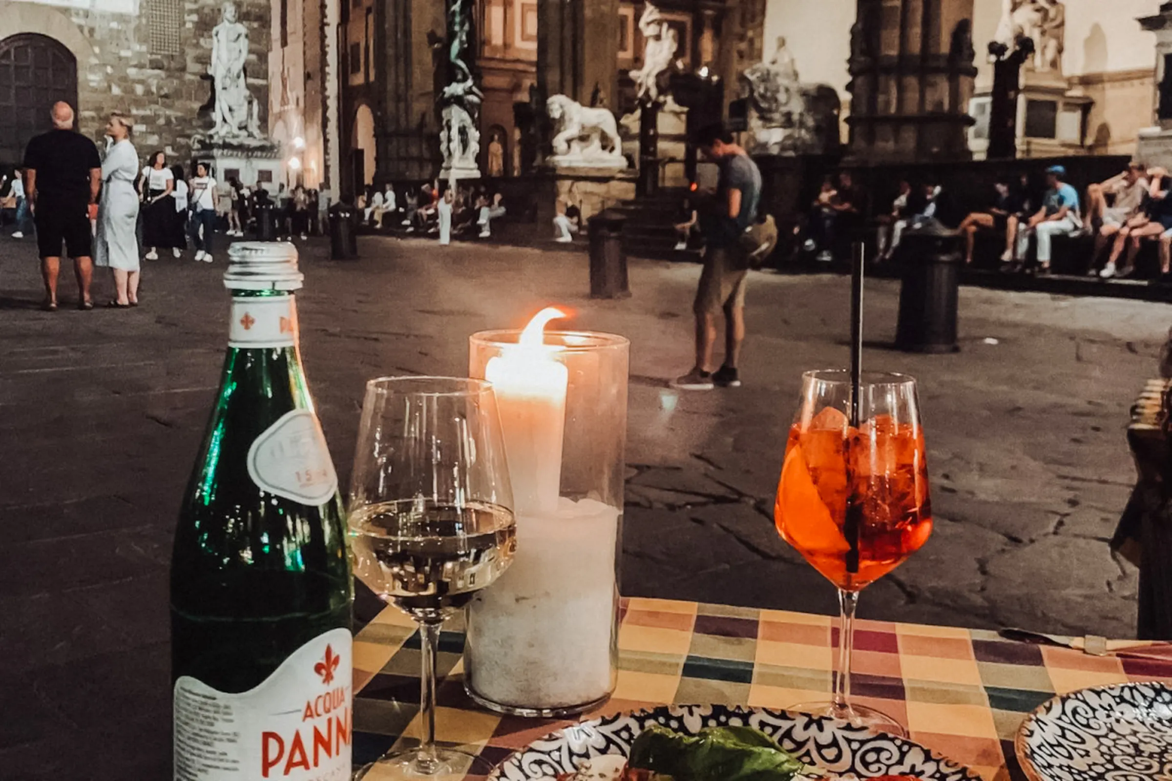 Candlelit dinner setup in Florence square with statues in the background.