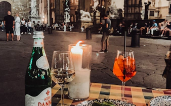 Candlelit dinner setup in Florence square with statues in the background.
