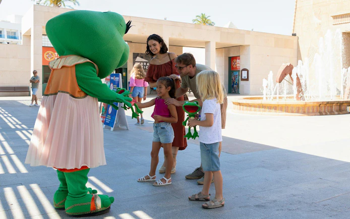 Children meeting a green mascot at Terra Mitica theme park in Spain.