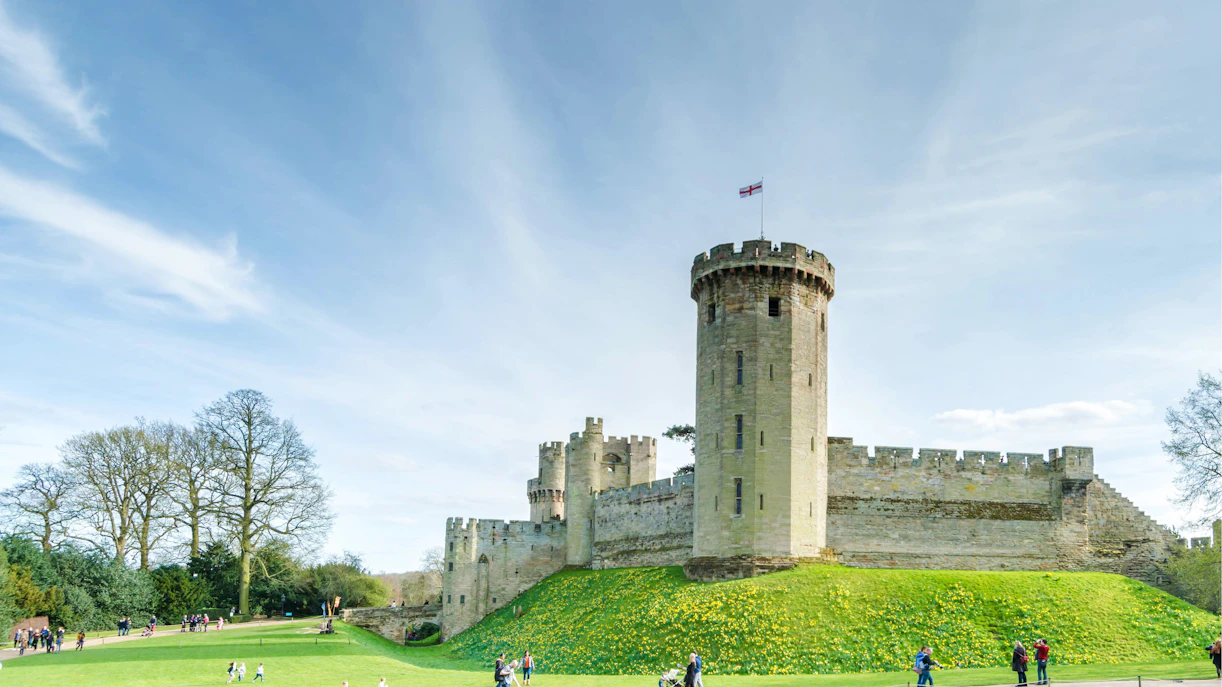 Warwick Castle East Front with tower and visitors on the lawn.