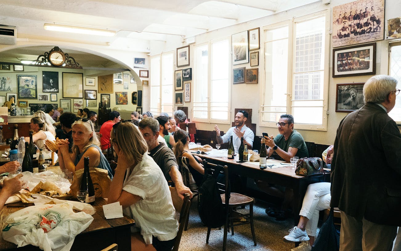People enjoying a meal at a traditional restaurant during a guided food tour in Bologna.
