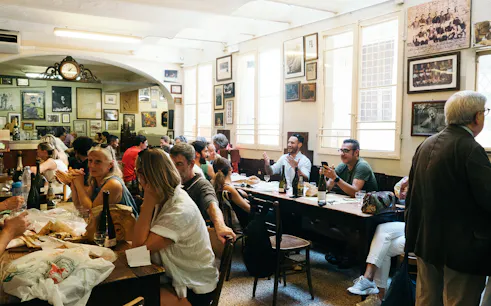 People enjoying a meal at a traditional restaurant during a guided food tour in Bologna.