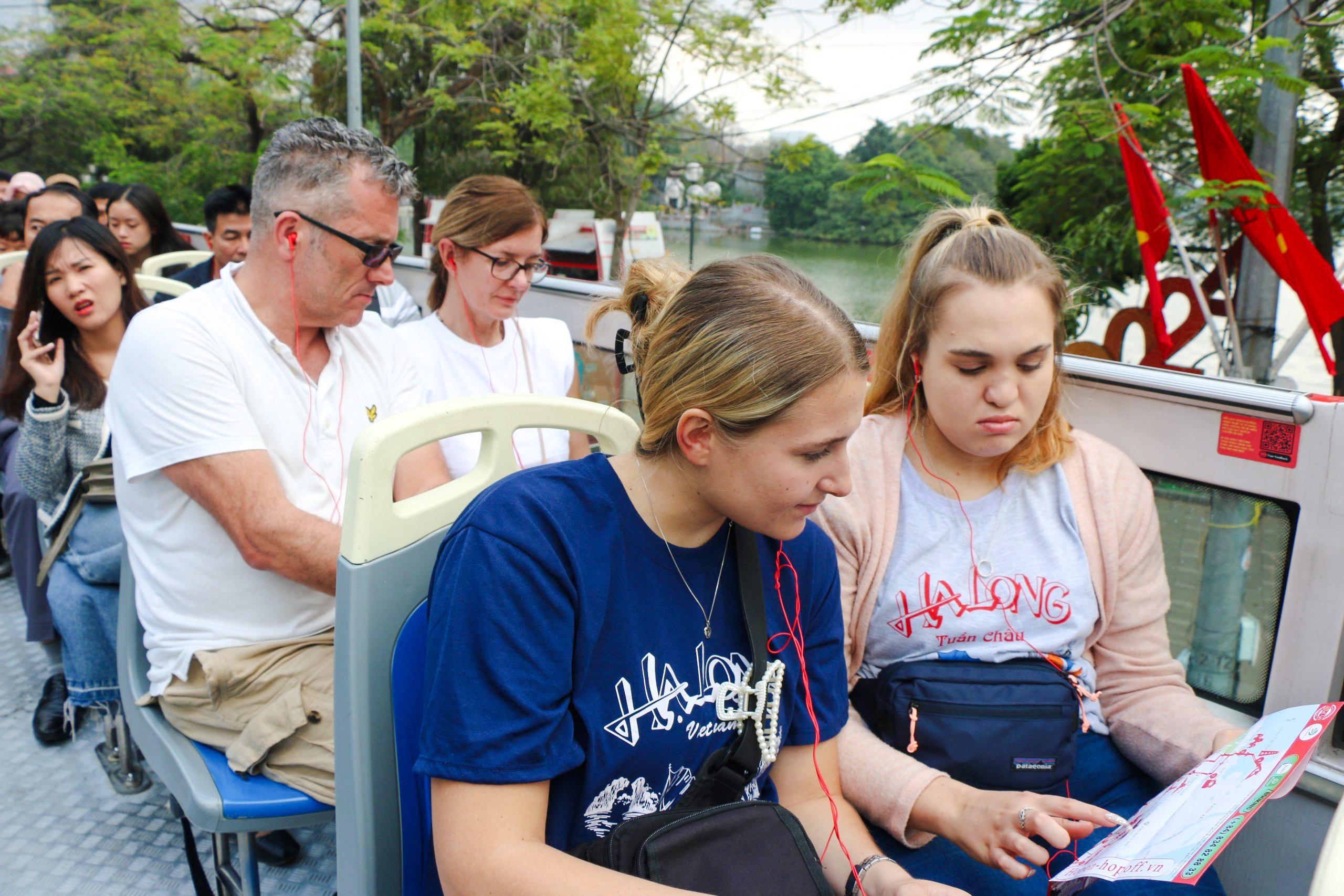 Passengers on a hop-on hop-off bus tour in Hanoi, Vietnam, looking at a map.