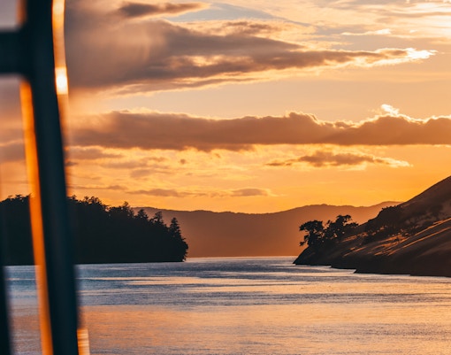 Sunset whale watching tour in Victoria with a boat on calm waters.