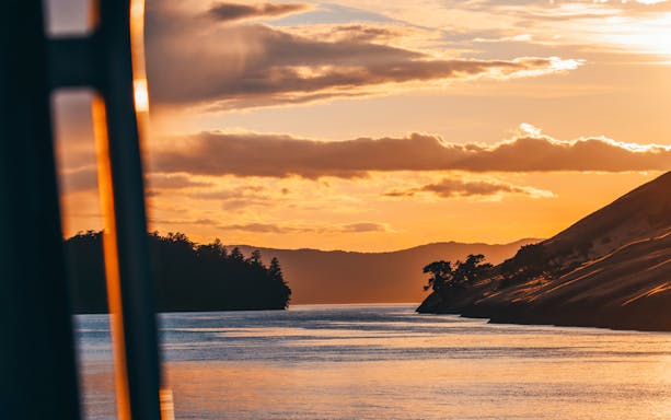 Sunset whale watching tour in Victoria with a boat on calm waters.