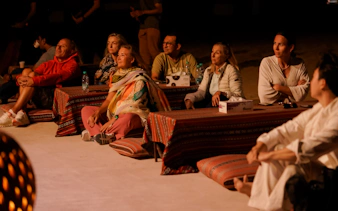 Guests seated on cushions enjoying an Abu Dhabi evening desert safari experience.