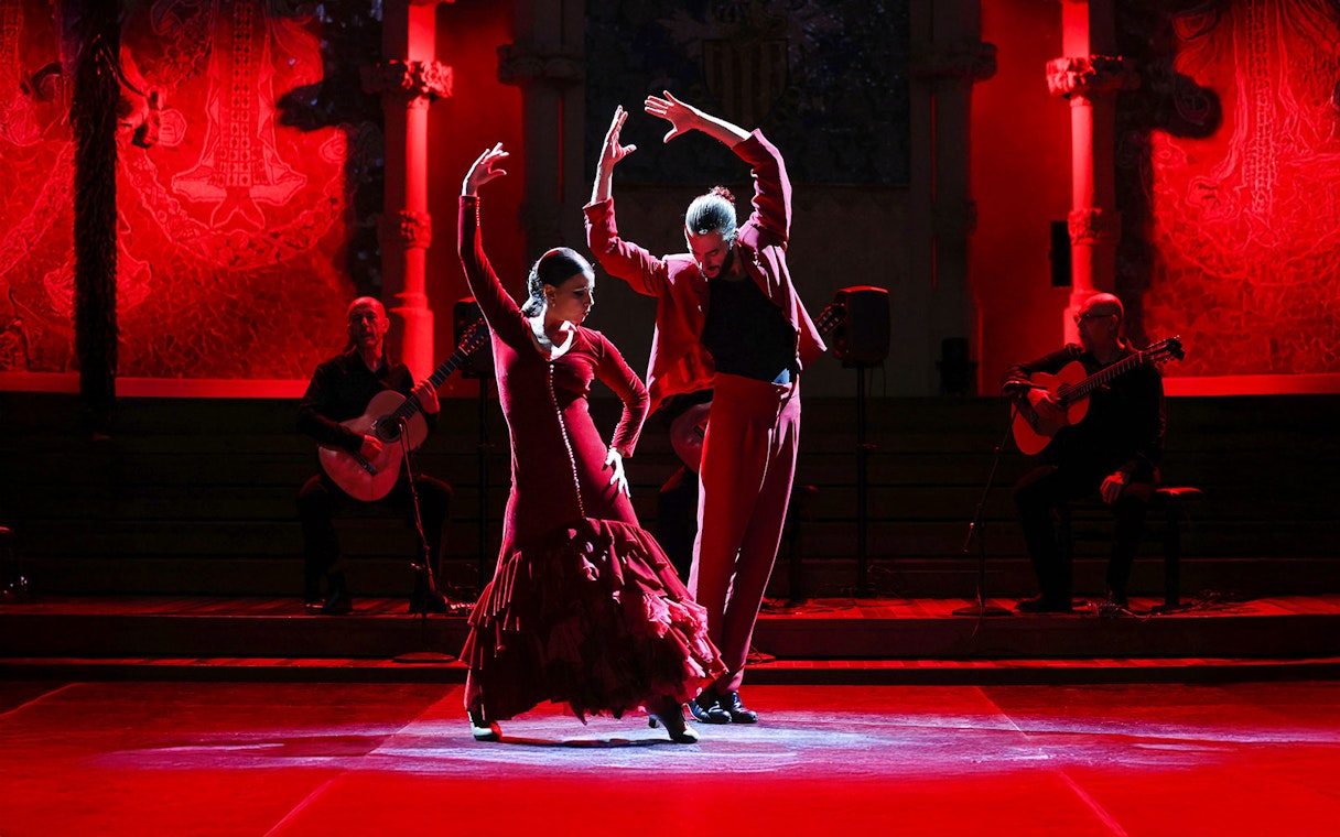 Flamenco dancers performing at Palau de la Música, Barcelona, with guitarists in the background.