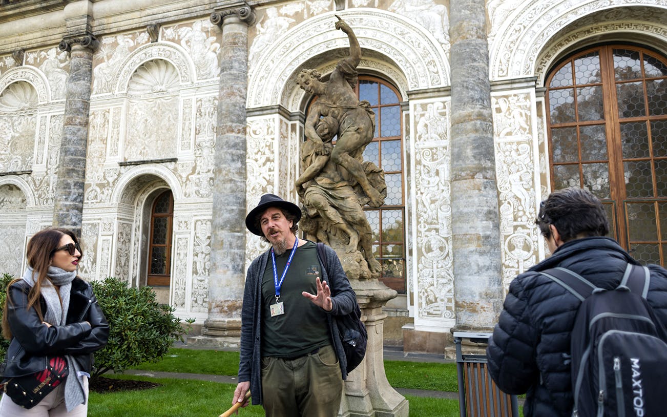 Tour guide explaining to tourists near a statue inside Prague Castle.