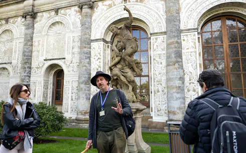 Tour guide explaining to tourists near a statue inside Prague Castle.