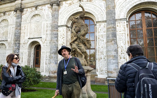 Tour guide explaining to tourists near a statue inside Prague Castle.