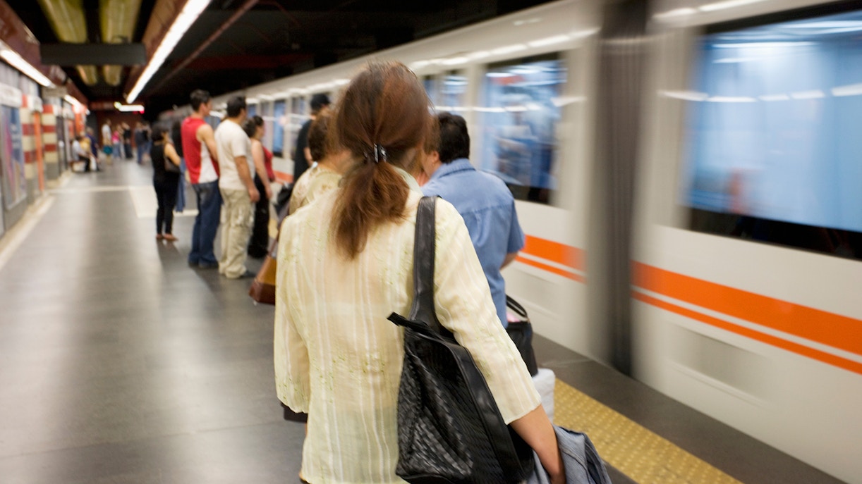 Rome metro station platform with passengers boarding a train.
