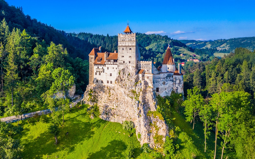 Bran Castle surrounded by lush green forest in Transylvania, Romania.