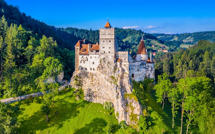 Bran Castle surrounded by lush green forest in Transylvania, Romania.