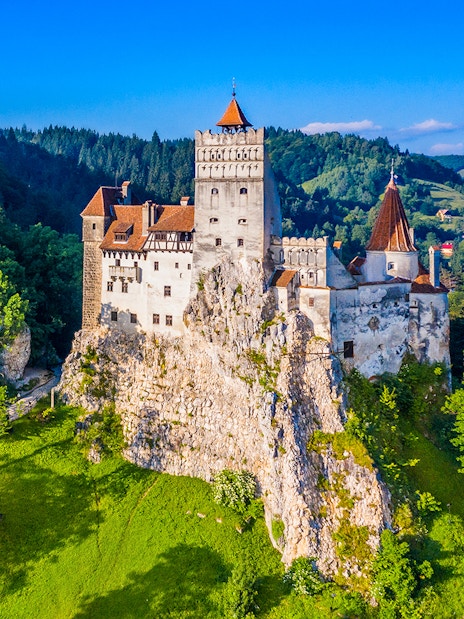 Bran Castle surrounded by lush green forest in Transylvania, Romania.