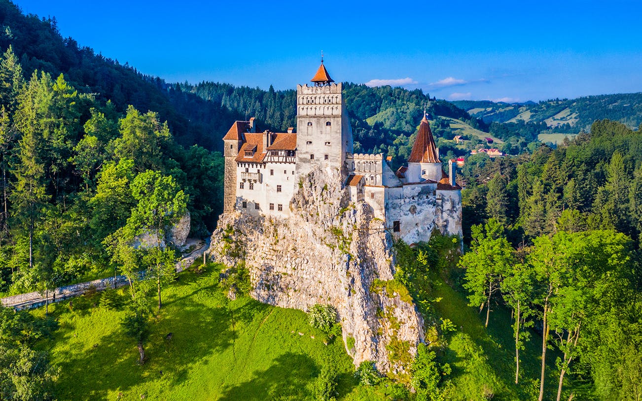 Bran Castle surrounded by lush green forest in Transylvania, Romania.