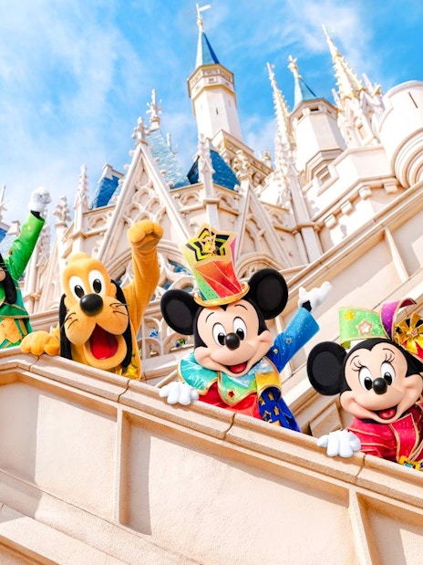 Mickey Mouse and friends in colorful outfits at Tokyo Disneyland castle.