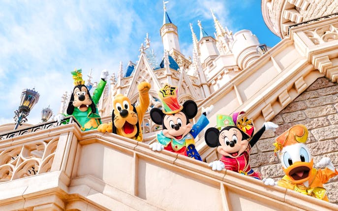 Mickey Mouse and friends in colorful outfits at Tokyo Disneyland castle.