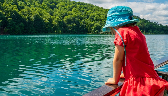 girl looking over the railing of a ferry cruising on Lake Kozjak