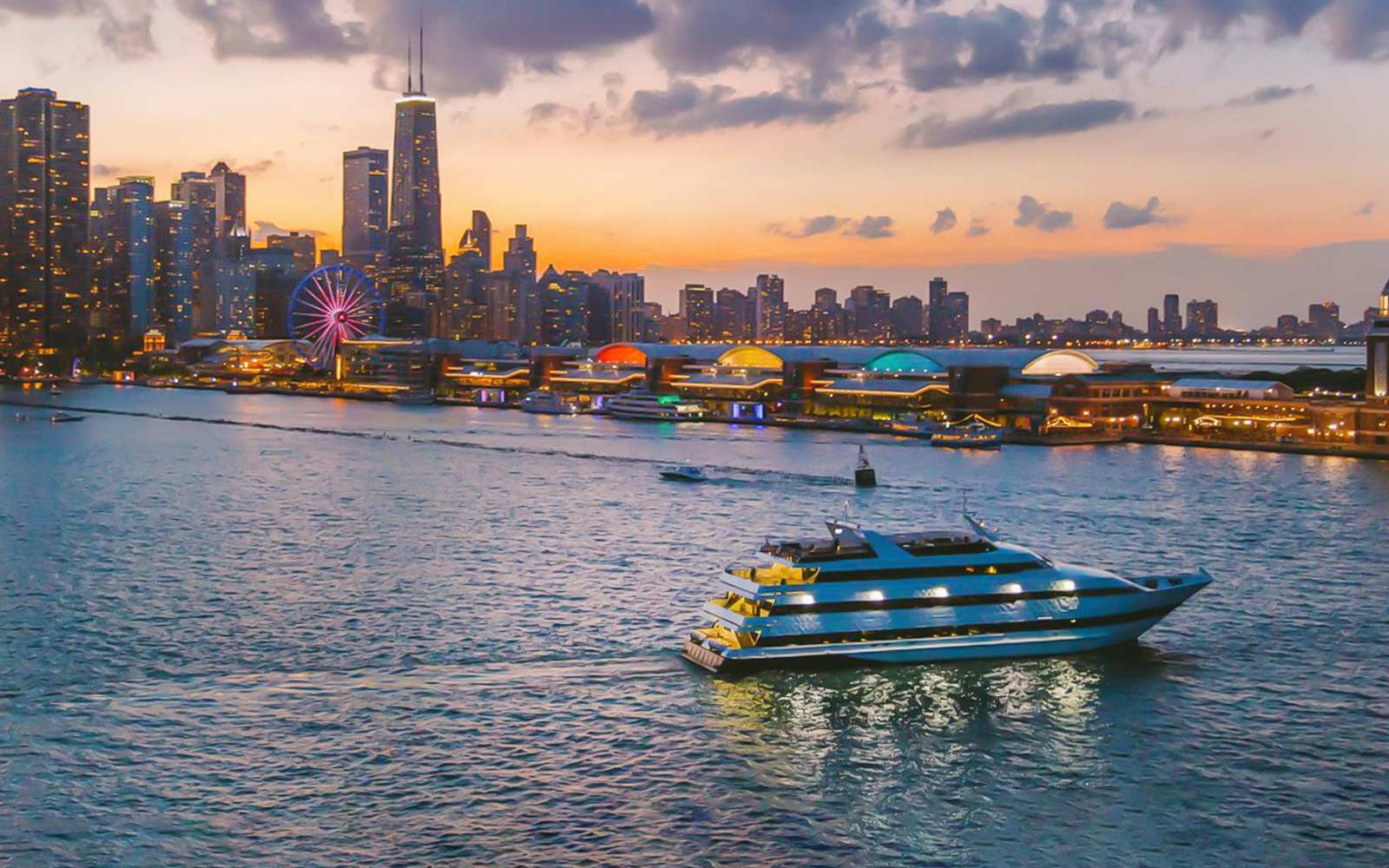 Cruise ship on Lake Michigan with Chicago skyline and Navy Pier at sunset.