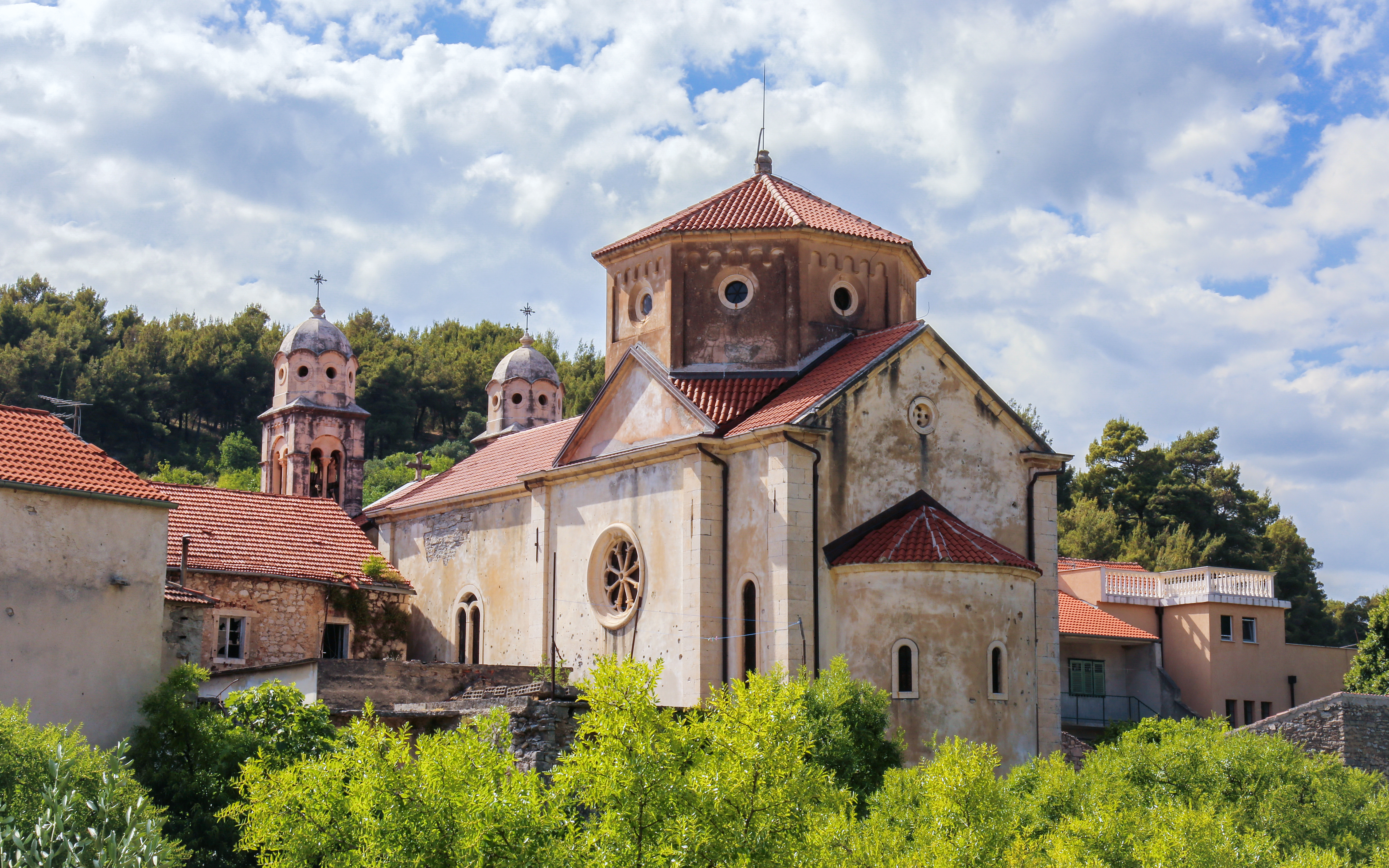St. Spiridon Church with red-tiled roof in Skradin, Dalmatia, Croatia, surrounded by greenery.