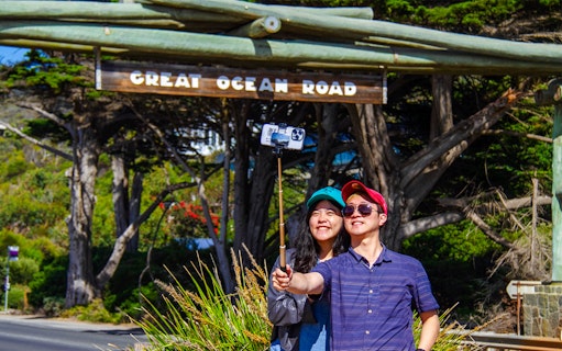 Tourists taking a selfie at the Great Ocean Road memorial arch.