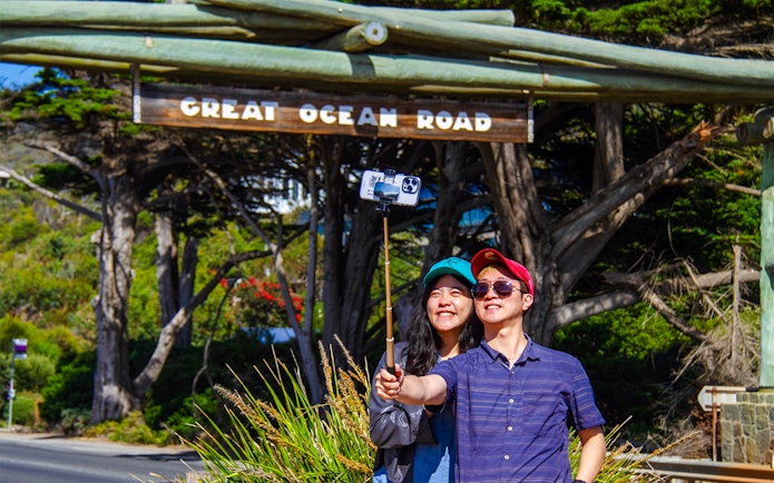 Tourists taking a selfie at the Great Ocean Road memorial arch.