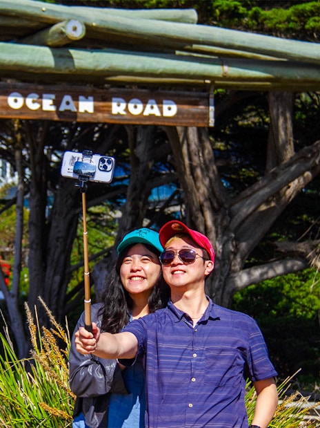 Tourists taking a selfie at the Great Ocean Road memorial arch.