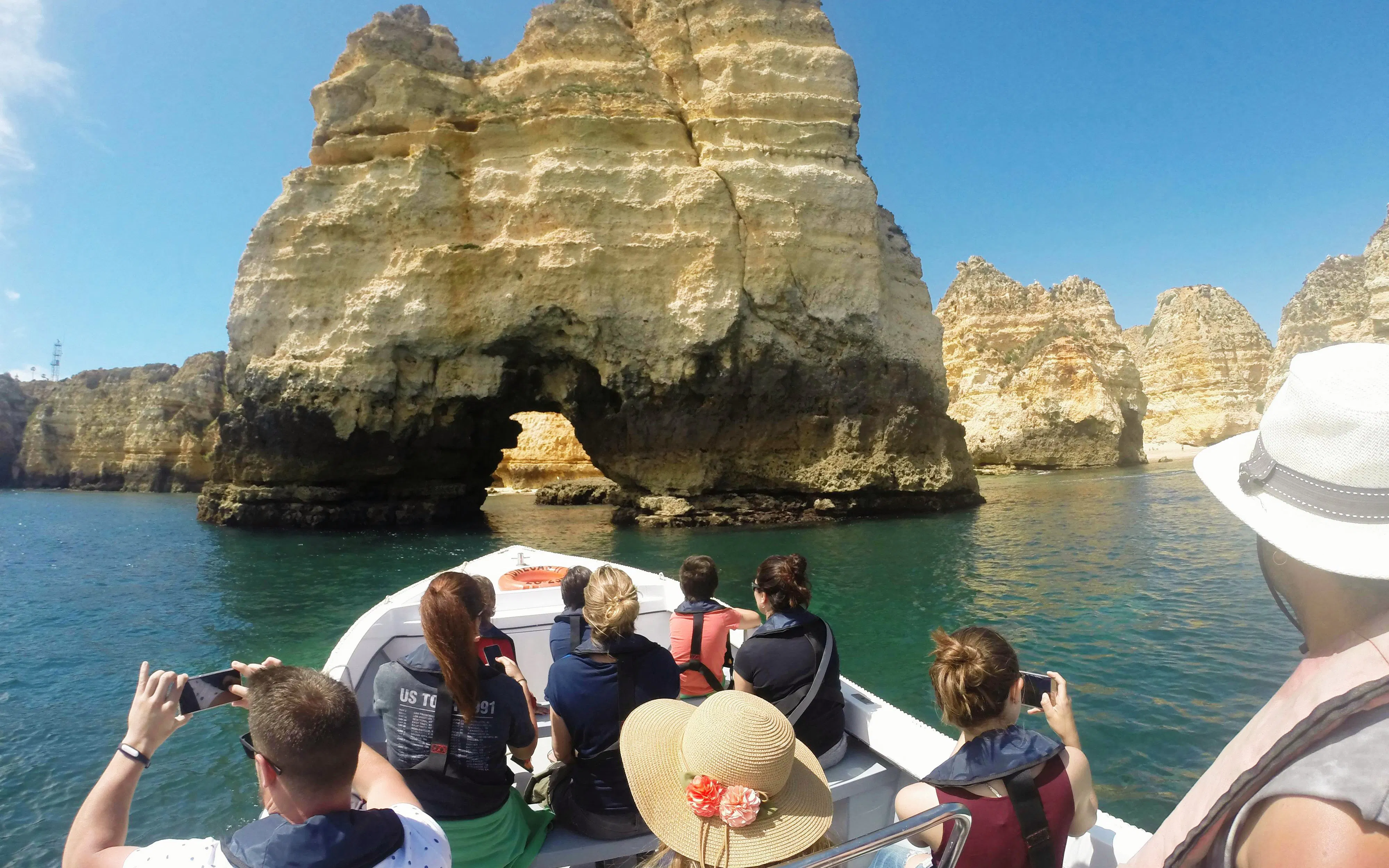 Boat tour approaching Ponta da Piedade rock formations near Lagos, Portugal.