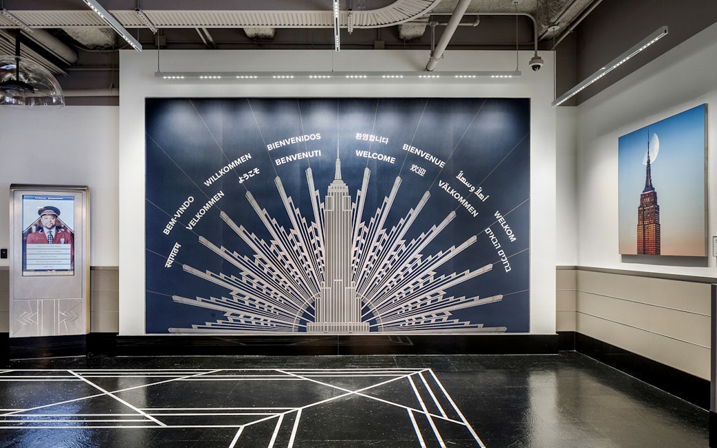 Empire State Building welcome mural with greetings in multiple languages.