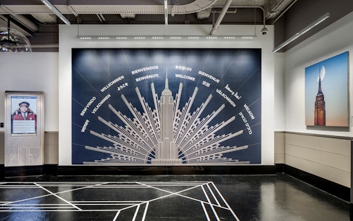 Empire State Building welcome mural with greetings in multiple languages.