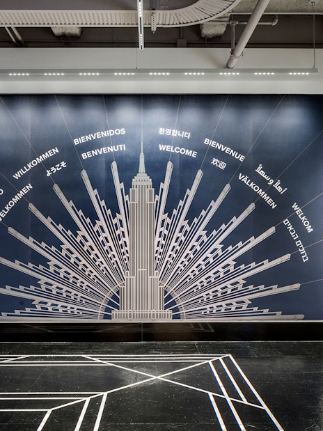 Empire State Building welcome mural with greetings in multiple languages.