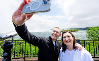 Tourists taking a selfie with Niagara Falls in the background during an augmented reality boat cruise.