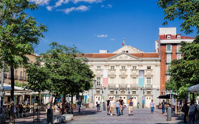 Plaza de Santa Ana in Madrid with people walking and cafes lining the square.