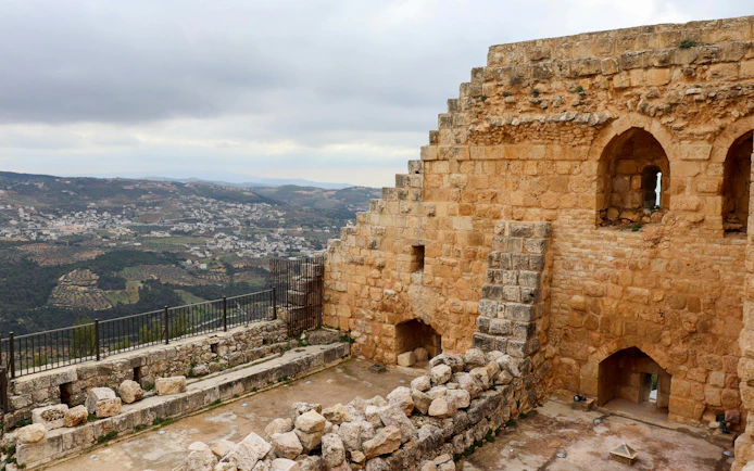 Ajloun Castle stone walls with arched windows overlooking Jordanian landscape.