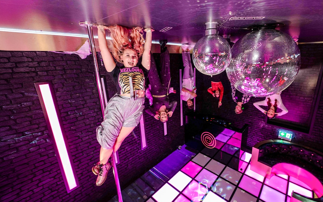 Visitors enjoying the upside-down room with disco balls at The Upside Down Amsterdam.