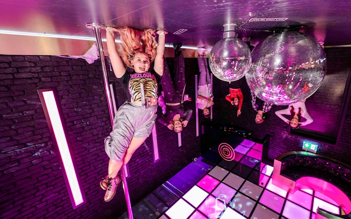 Visitors enjoying the upside-down room with disco balls at The Upside Down Amsterdam.