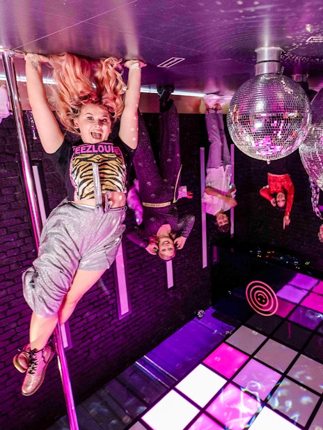 Visitors enjoying the upside-down room with disco balls at The Upside Down Amsterdam.