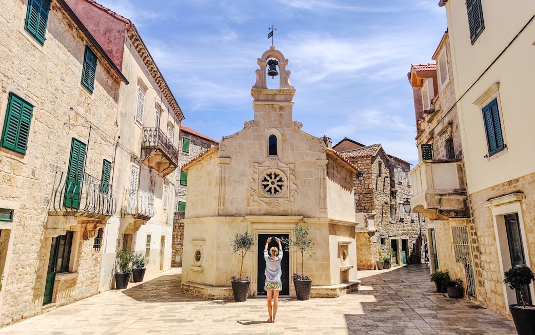 Guest exploring historic stone buildings in Jelsa, Croatia.