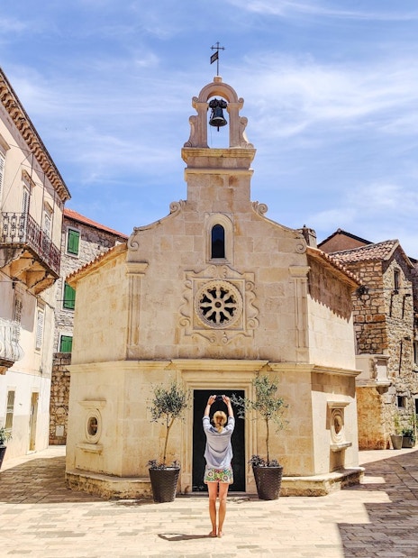 Guest exploring historic stone buildings in Jelsa, Croatia.